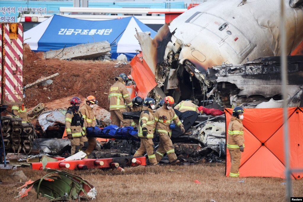 Firefighters carry the body of a passenger from the wreckage of a Jeju aircraft that crashed after it went off the runway at Muan International Airport, in Muan, South Korea, Dec. 29, 2024.